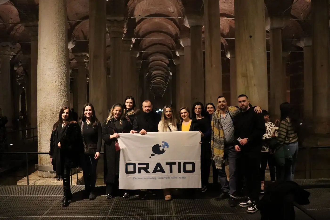Das Team mit Oratio-Fahne in einer historischen Säulenhalle