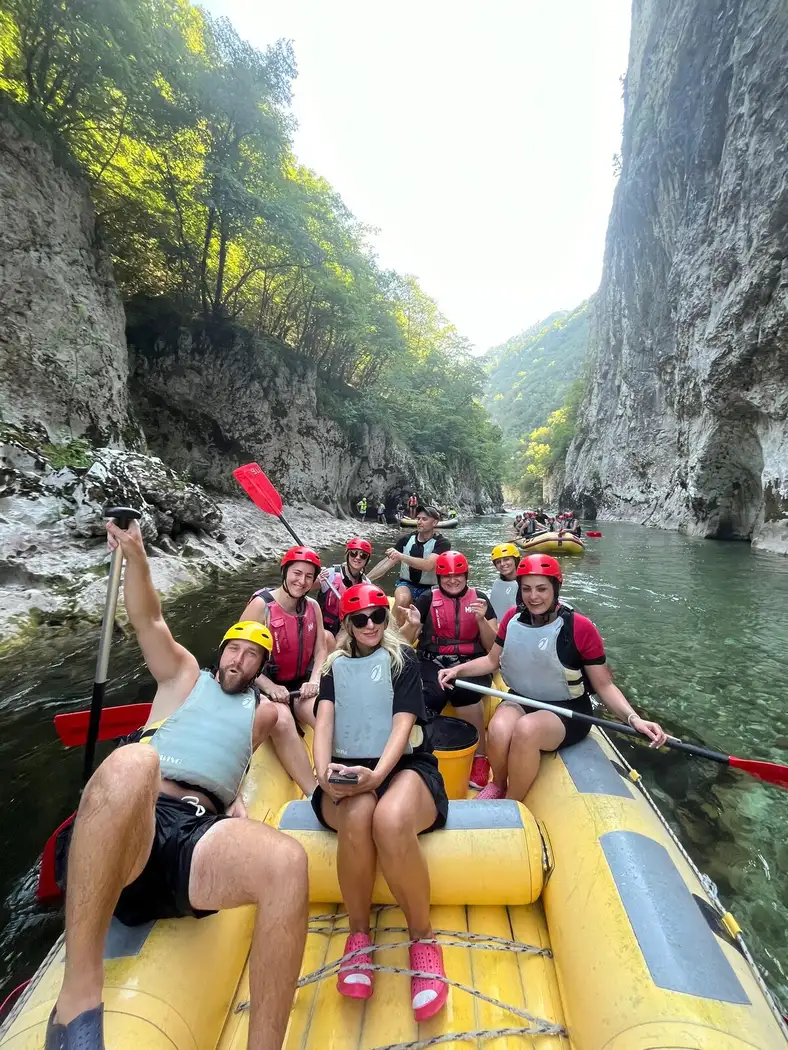 The team raising their paddles in the raft