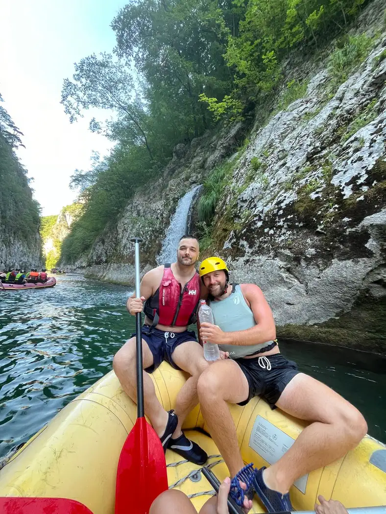 Two colleagues on the raft in front of a waterfall