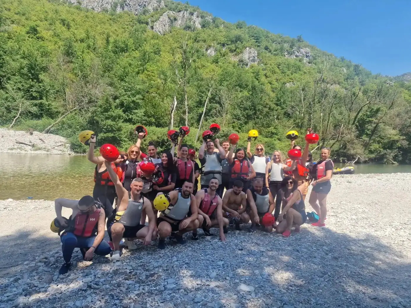 The team on the Neretva riverbank, helmets raised