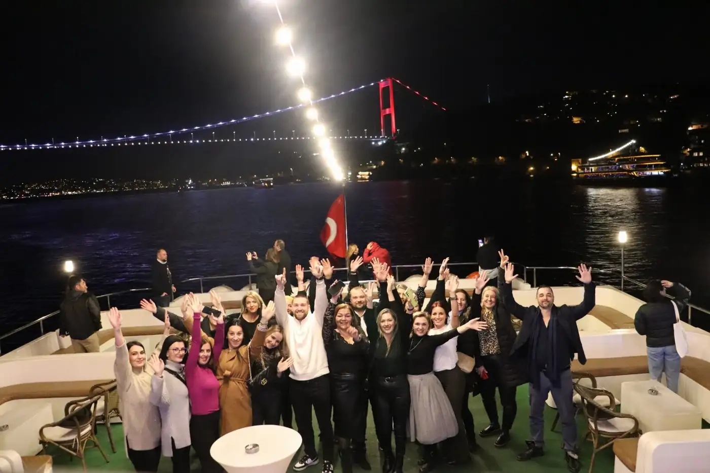 Das Team bei einer Bootsfahrt über den Bosporus unter der beleuchteten Brücke